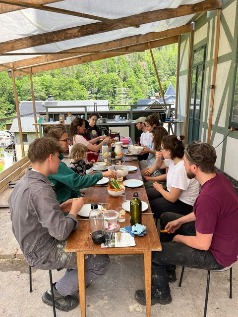 Gemeinsames Essen an einer langen Tafel unter einem Vordach